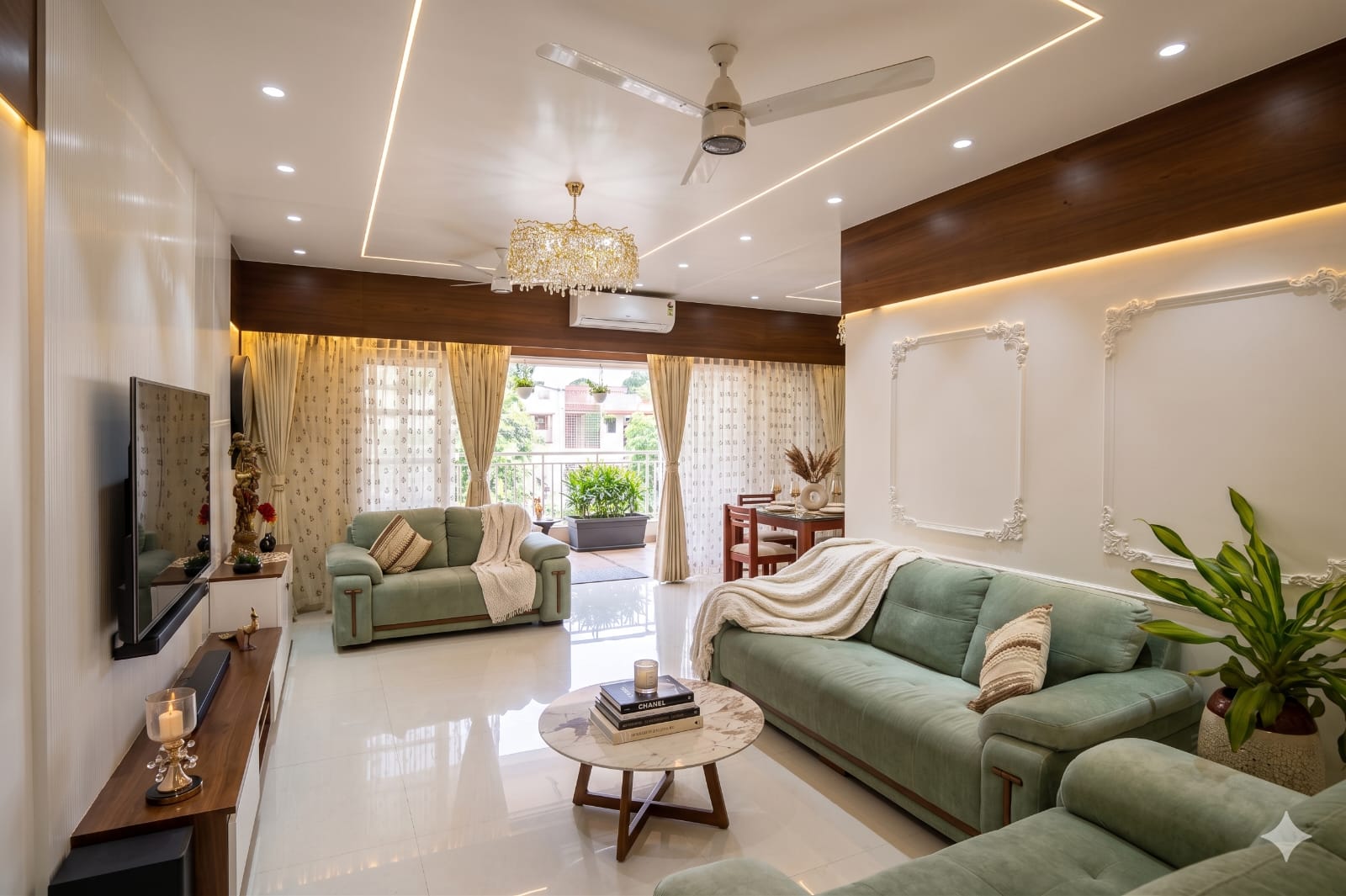 Modern living room with sage green sofas, warm wood accents and crystal chandelier